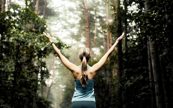 Runner in Woods with Hands Raised